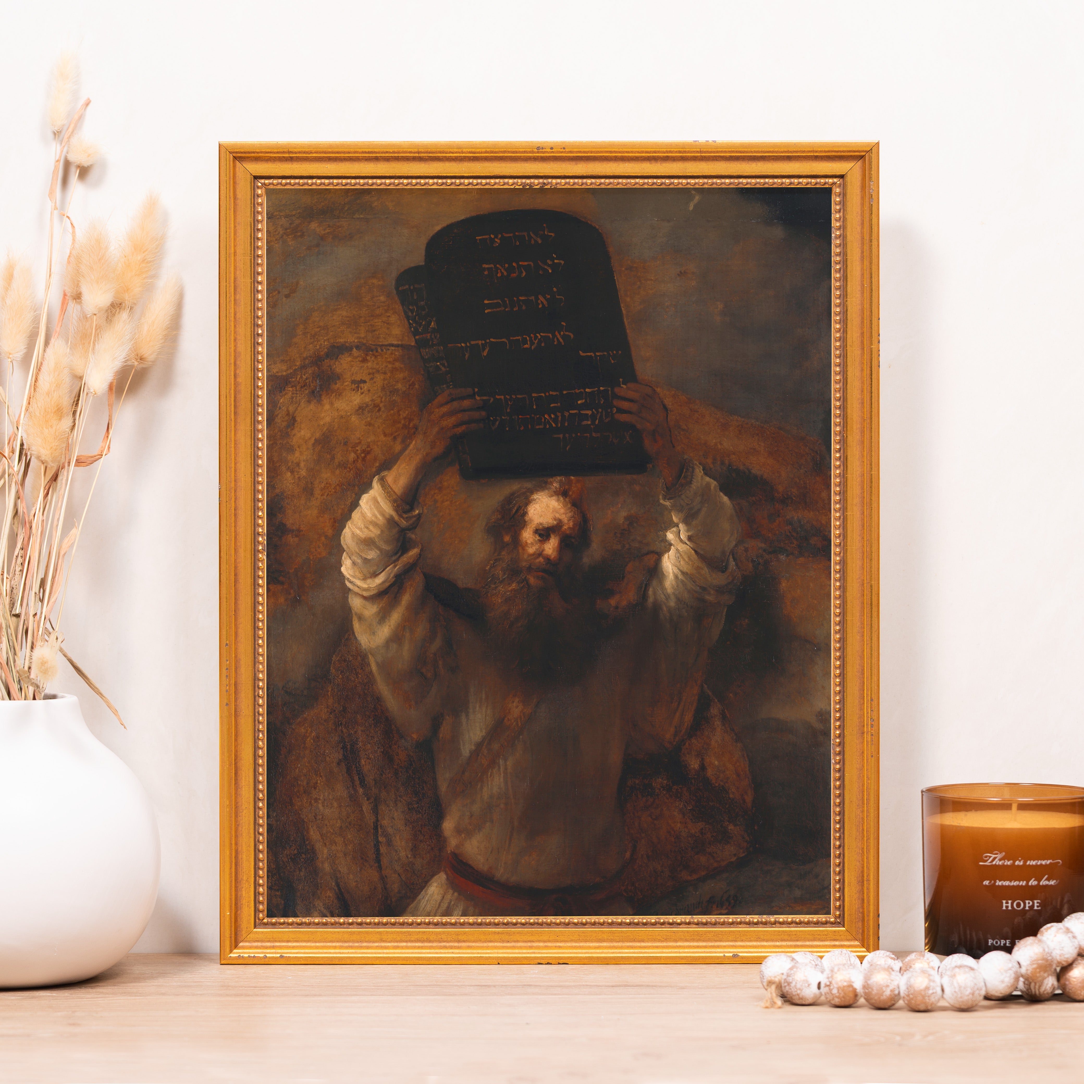 Framed art print of Moses holding the Ten Commandments in Hebrew, ornate gold frame, brown tones.