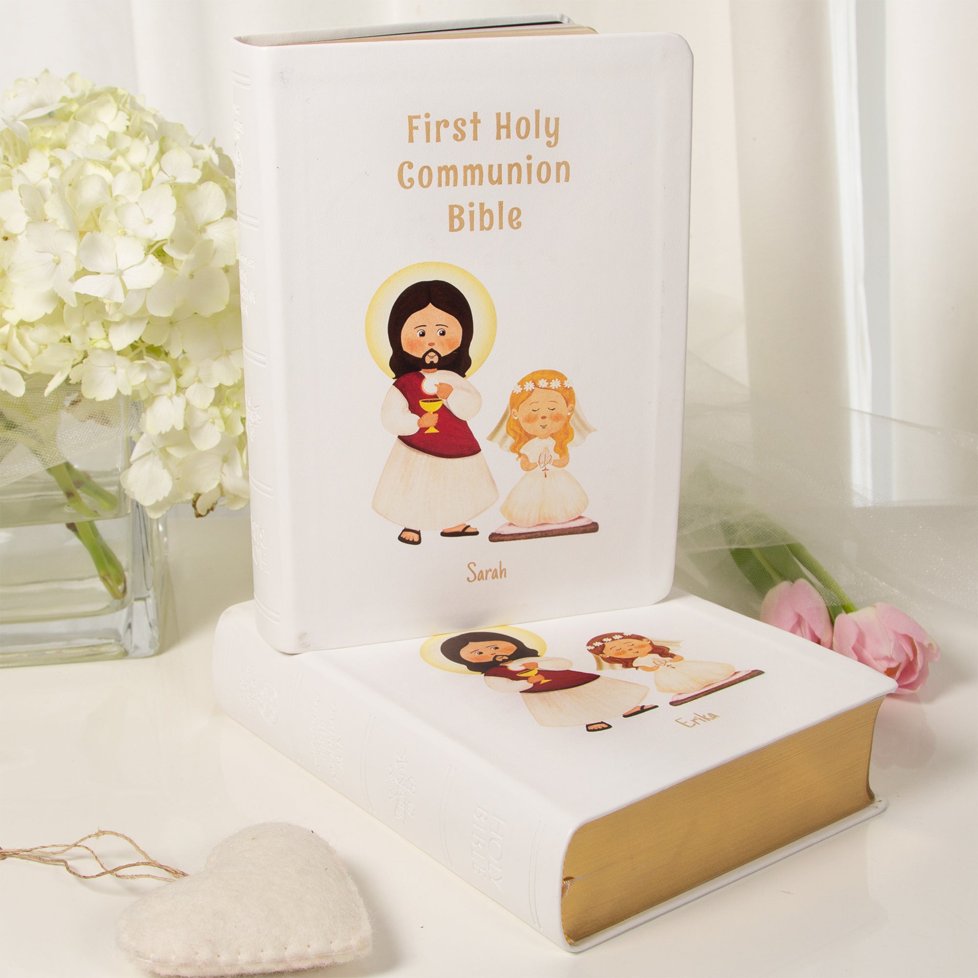 White, personalized First Holy Communion Bible with cartoon graphics of Jesus and a girl.