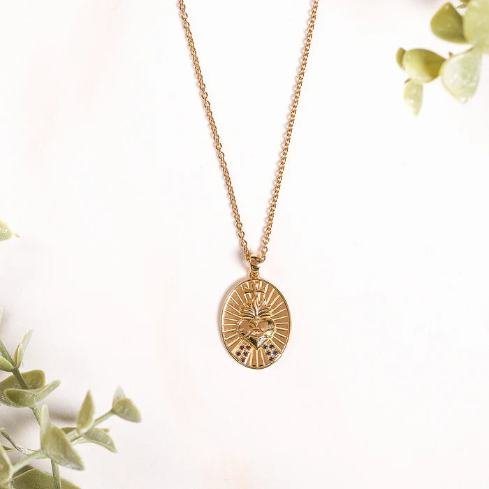Gold Sacred Heart pendant necklace on a light background.