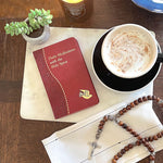 Daily Meditations with the Holy Spirit book on a table with a fancy coffee, a succulent, and a wooden rosary.