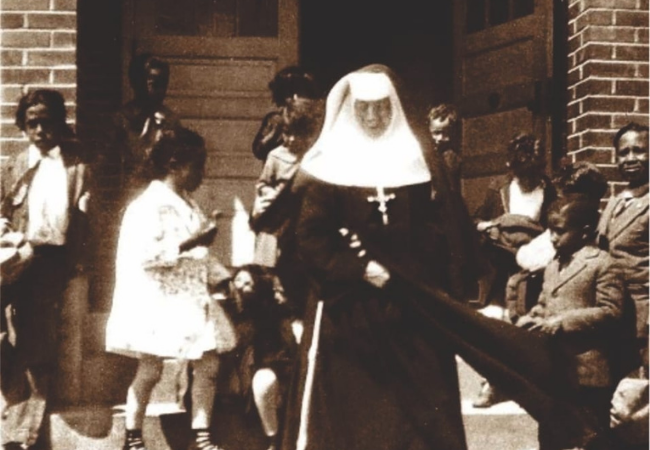 St. Katharine at Belmont Abbey College with young children around her.
