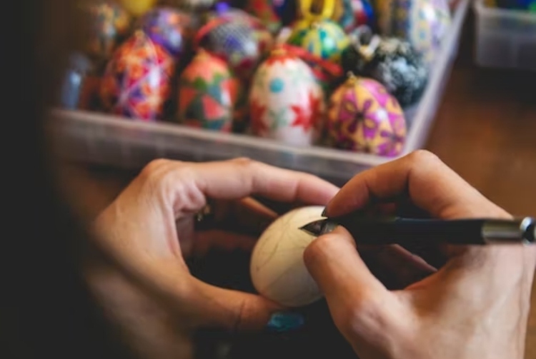 An artist draws the first design on a pysanka before beginning to wax and dye the egg.